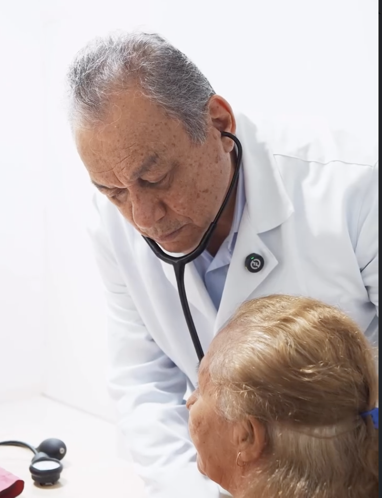Dr. Walber examinando uma paciente com estetoscópio no consultório